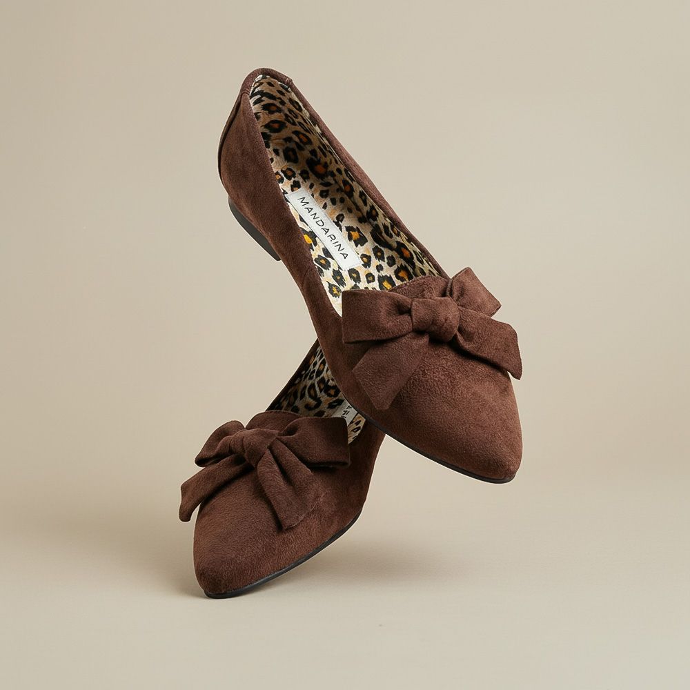 Brown suede shoes with bow details on a beige background