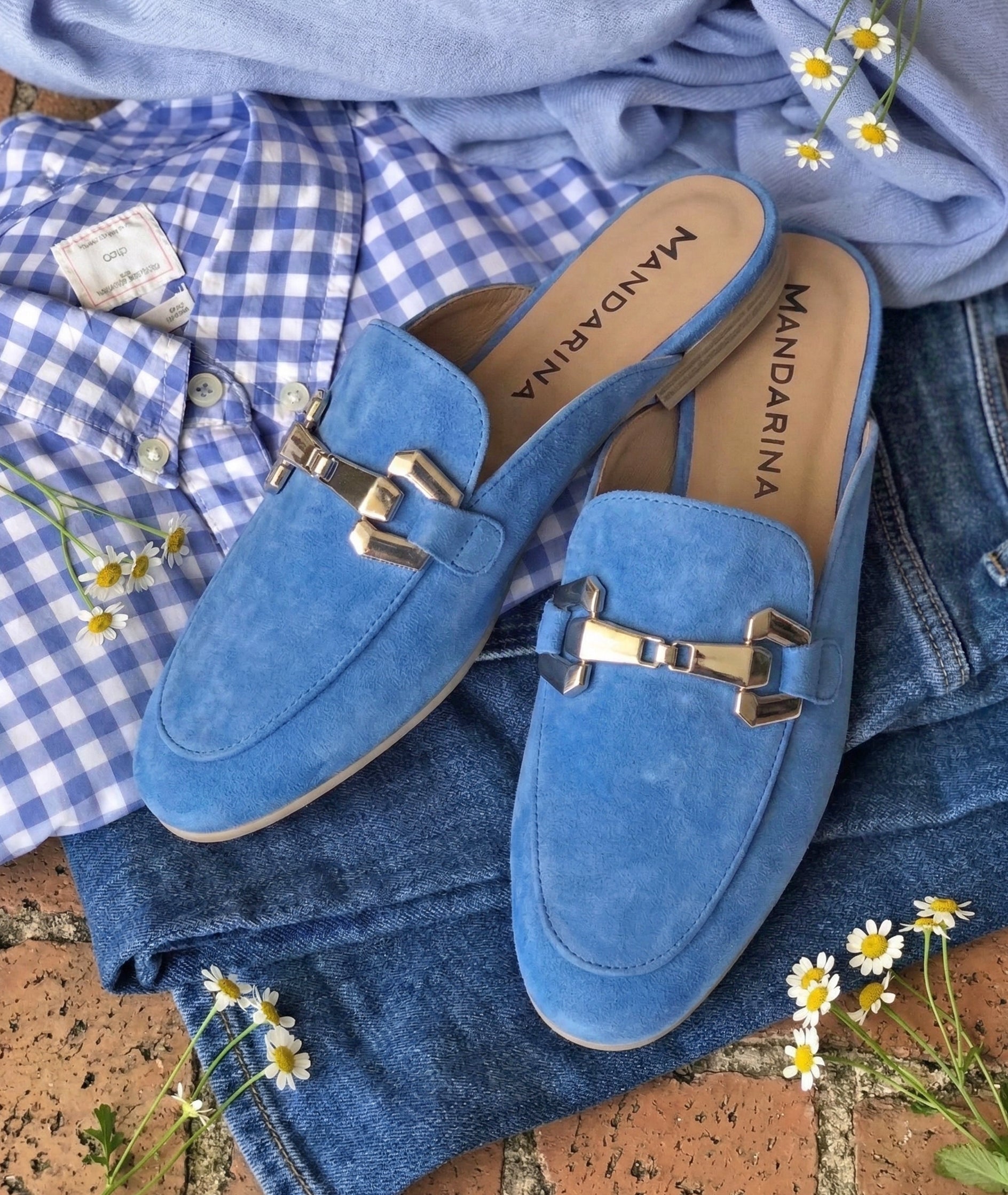 Blue suede loafers with metallic buckles on a denim fabric background