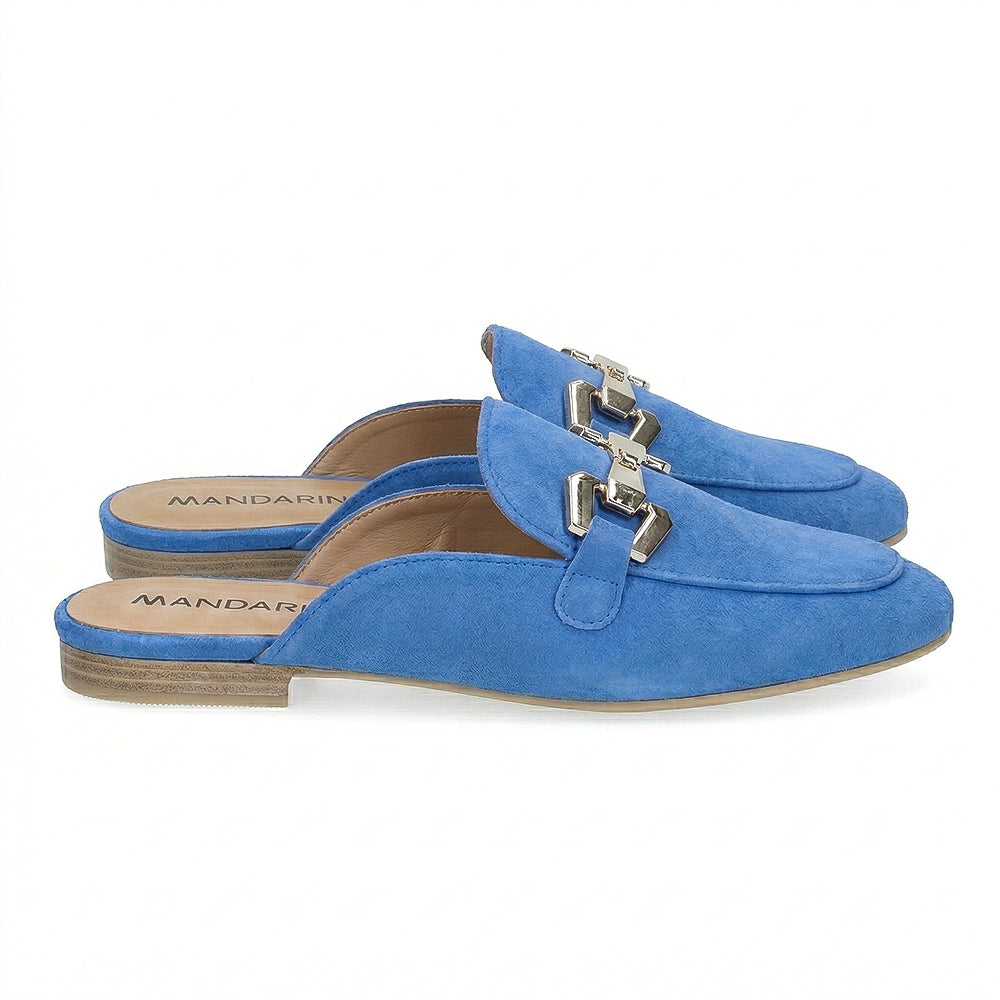 Blue suede mule loafers with a silver buckle on a white background