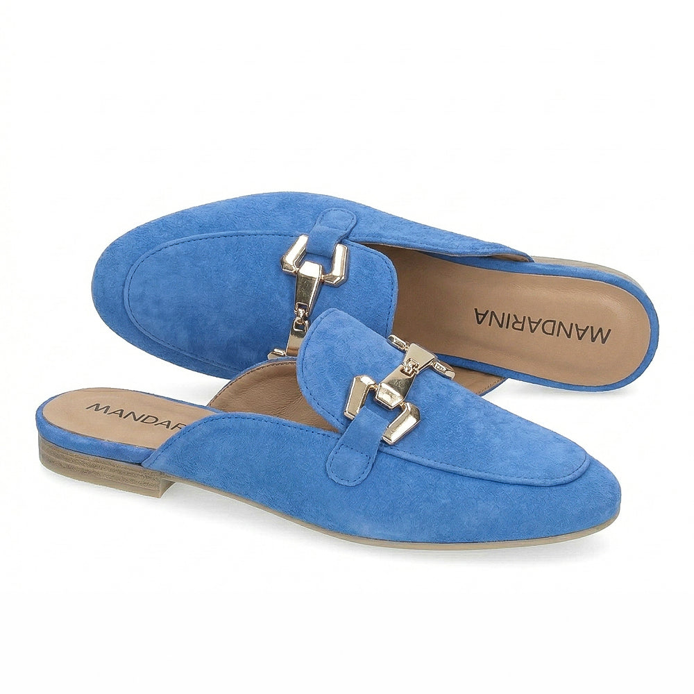 Blue suede mules with gold buckles on a white background
