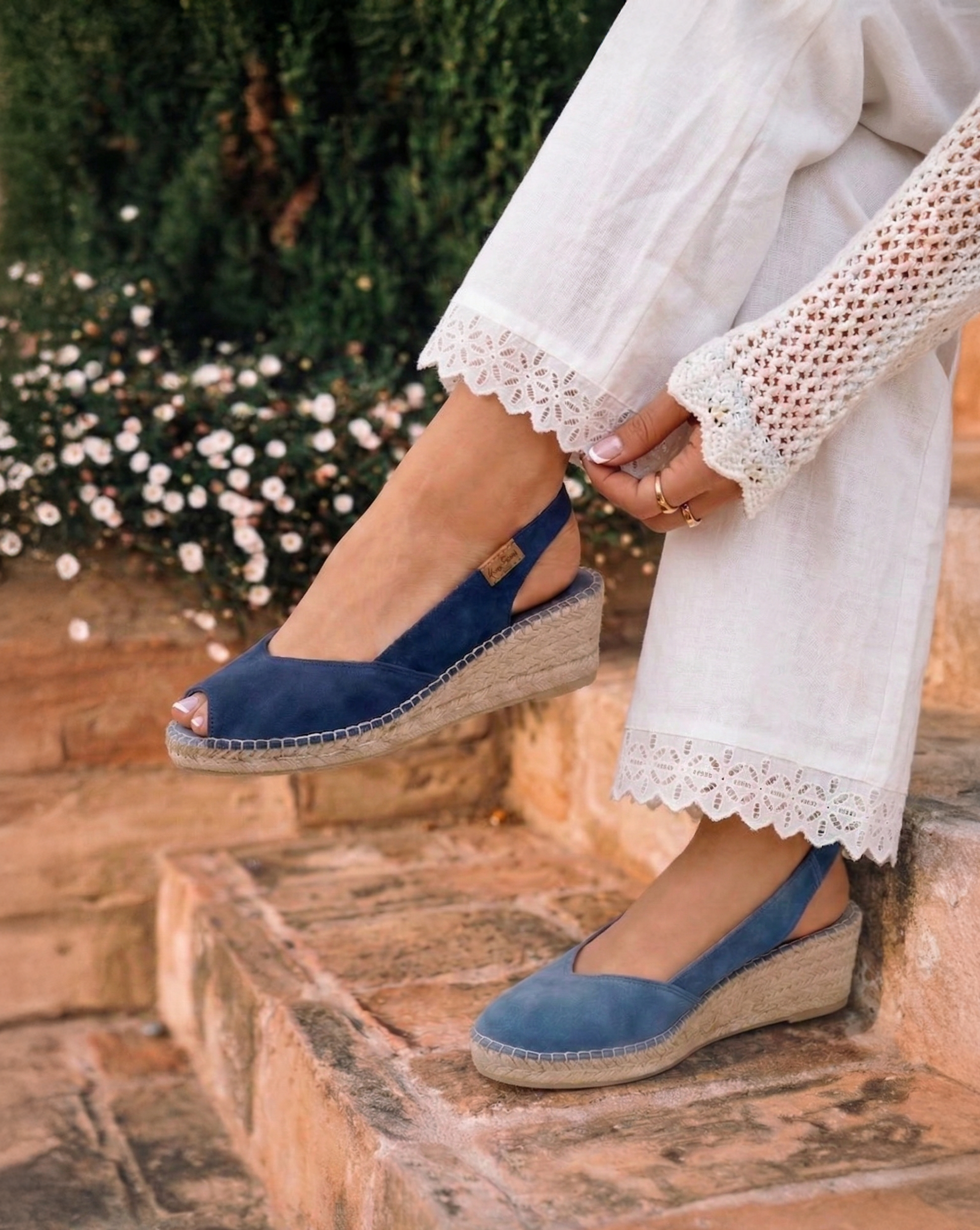 Person wearing blue wedge sandals on stone steps with a blurred natural background