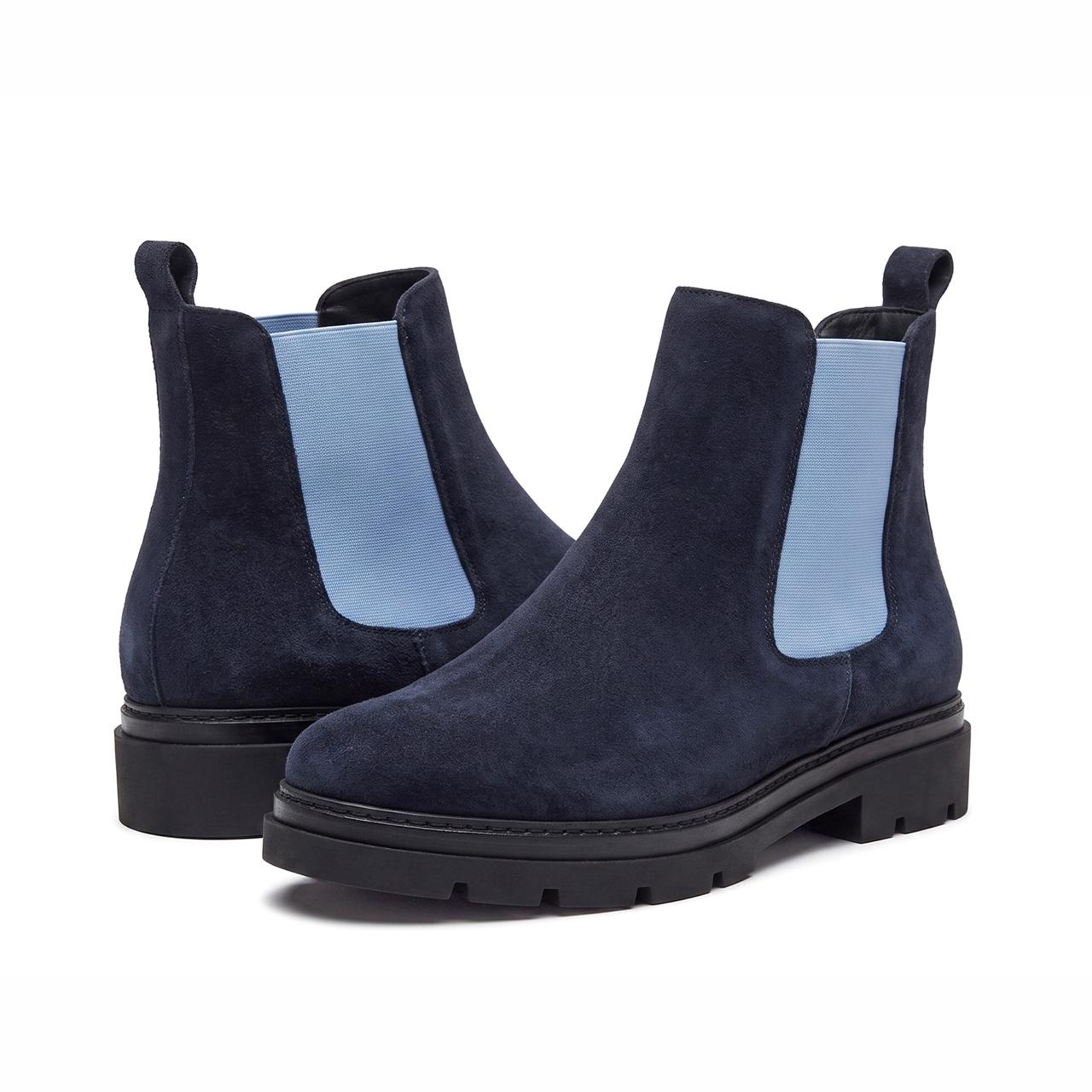 A pair of navy blue suede Chelsea boots with light blue elastic side panels and chunky black soles, shown on a clean white background.